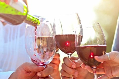 Several couples pouring a bottle of wine in the sunshine