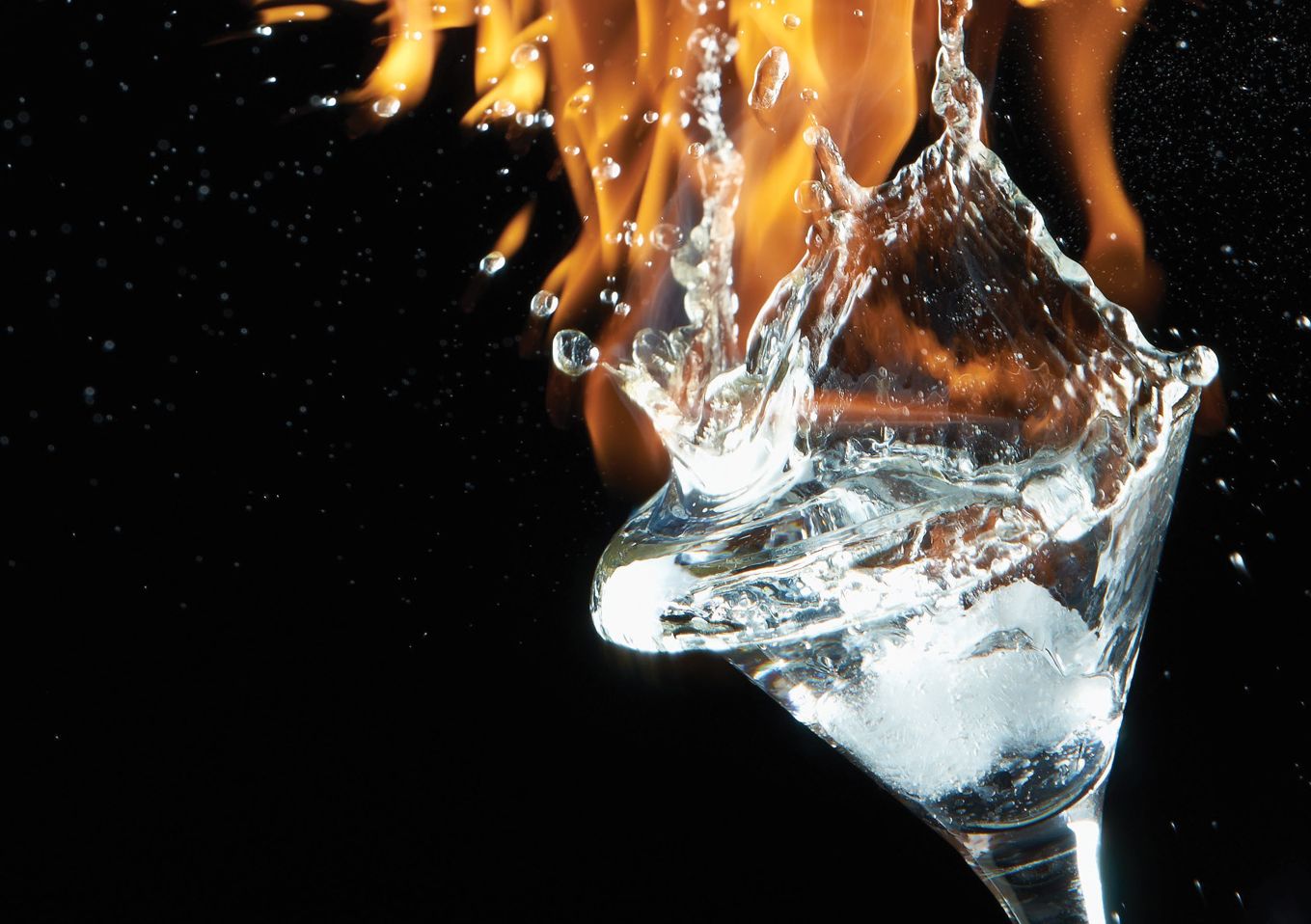 An image on a martini glass on a dark background with fire in the background