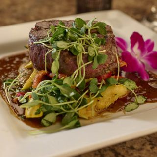 A deliciously prepared filet mignon with micro greens and seasonal vegetables